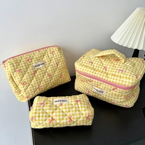 Three-piece set of yellow checkered quilted cosmetic bags with pink bow pattern detail