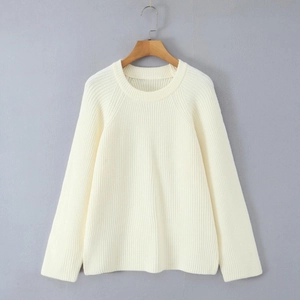 Detail of cream-white knitted long sleeve sweater showing textured knit and crew neck