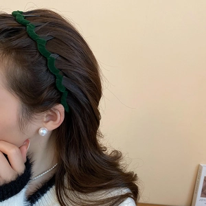 Close-up of velvet wavy headband in dark green with inner teeth for secure hair styling