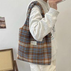 Detail shot of a vintage plaid canvas tote bag in navy and brown worn by a model