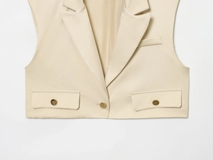 Détail du gilet beige à revers avec boutons dorés et texture de tissu premium