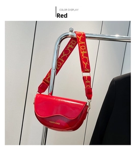 Detail view of red glossy saddle bag with golden lettering and jacquard strap