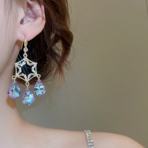 Detail of drop tassel earrings featuring aurora crystal accents in a star frame