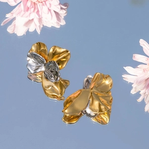 Macro shot of gold and silver two-tone floral earrings with a polished metal texture