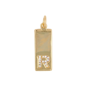 Macro detail of gold rectangular pendant with zircon letter R on white background