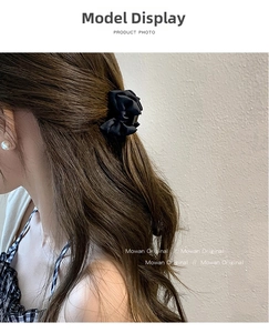 Close-up of a black satin rose hair claw clip styled on a model in a side-view profile