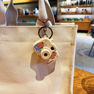Cute Capybara camera keychain with light hanging on a beige canvas bag accessory