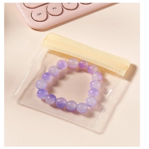 Purple beaded bracelet in a clear PVC jewelry storage bag on a pink desk background