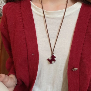 Detailed view of a red rocking horse pendant with cubic zirconia on a black cord