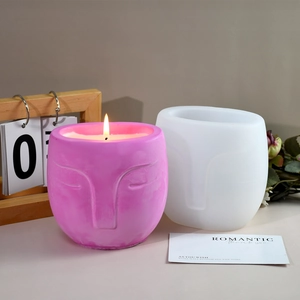 Detail of artistic face silicone mold with finished pink candle in minimalist design