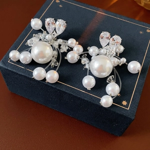 Macro detail of luxury pearl earrings with zircon crystals on a dark blue gift box