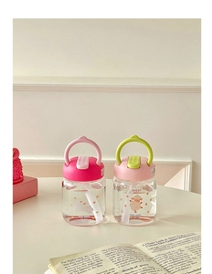 Detailed view of pink and green portable glass water bottles with cute animal illustrations