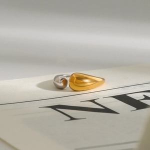 Macro shot of two-tone gold and silver drop-shaped ring on a newspaper background