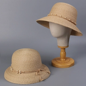 Detail eines Raffia-Strohhuts mit Holzperlenbesatz und feiner geflochtener Schleife
