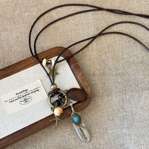 Vintage bohemian necklace with wooden rings and bronze feather pendants on brown cord