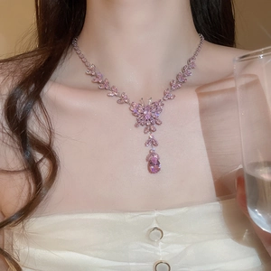 Detail of pink crystal butterfly pendant necklace with drop stone on a white dress