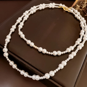Vue détaillée du collier de perles multicouche avec fermoir doré sur cuir marron