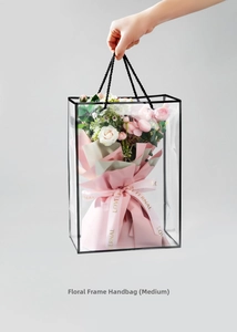 Close-up of medium-sized transparent gift bag with black trim and pink rose bouquet