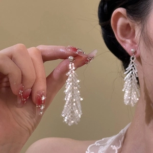 Elegant long white beaded fringe earrings with pearl stud on model in profile