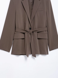 Detail of coffee brown women blazer featuring waist tie design and flap pockets