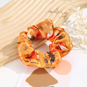 Detail of Halloween satin scrunchie with orange print on a wooden tray with dried flowers