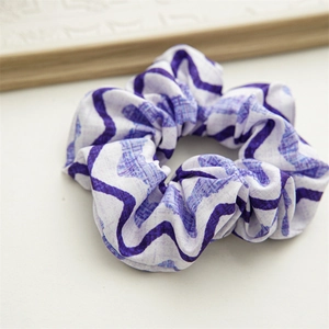 Close-up of purple and white wavy checkered fabric scrunchie with elastic hair tie detail