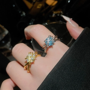 Detailed view of criss-cross zircon rings in gold and silver plating with blue stones