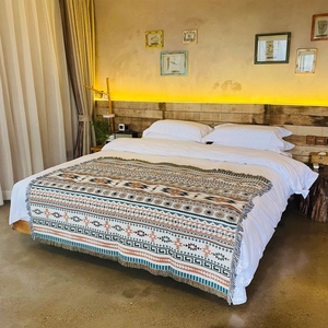 Bohemian geometric woven blanket with tassels styled on a white bed in a cozy bedroom