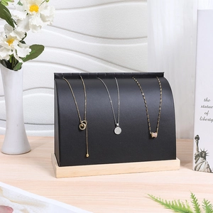 Detail of black leather necklace display stand with natural wood base in a modern setting