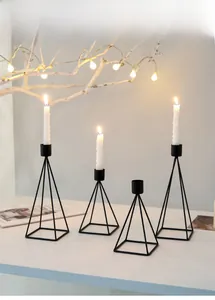 Detail of four black geometric metal candle holders in minimalist pyramid design