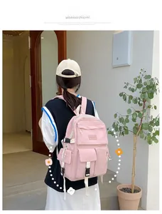 Rear view of a pink multi-pocket nylon backpack worn by a model in a modern outdoor setting
