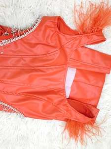 Détail du haut corset en similicuir orange avec franges en strass et bordure en plumes