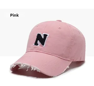 Detailed close-up of pink baseball cap with N patch and vintage distressed brim finish
