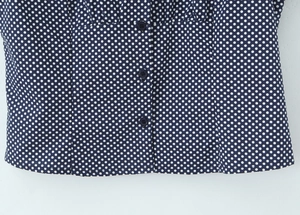 Detailed view of the button-down hem on a navy blue polka dot puff sleeve blouse