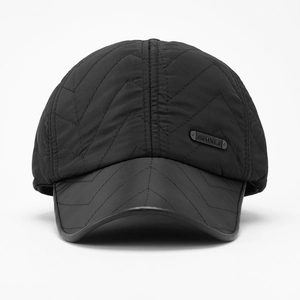 Detail of black quilted baseball cap featuring V-shaped stitching and matte metal logo