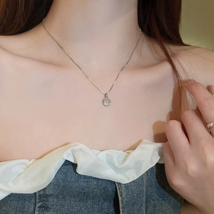 Close-up of elegant opal pendant necklace and gold ring on woman's neck and hand