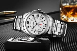 Luxury men's silver watch with roman numerals beside business accessories and car key