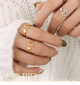 Close-up of gold and silver heart and arrow adjustable rings worn by a model