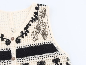 Detail of crochet knit vest featuring floral embroidery and dark brown buttons