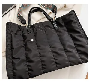 Detailed view of black quilted nylon tote bag with decorative vintage wide shoulder strap