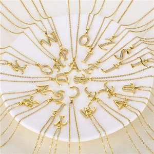 Collection of gold letter pendants with pave-set sparkling zircon on white background