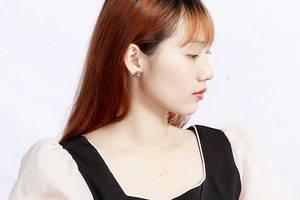 Close-up of a silver geometric rhombus earring shown on a model for a modern look