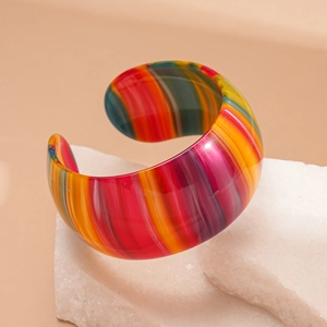 Gros plan d'un bracelet ouvert en acétate rayé coloré sur des pierres blanches