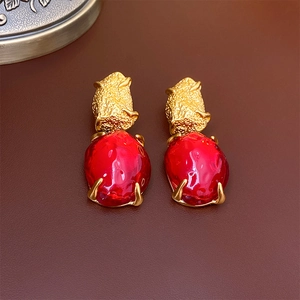 Detailed macro view of vintage gold textured earrings with irregular red gemstone drops