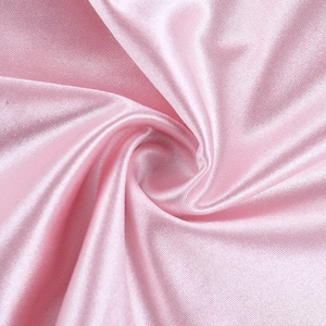Vue macro détaillée du tissu en satin rose brillant montrant des textures drapées