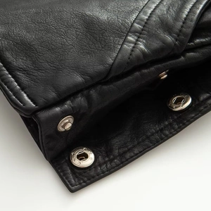 Detail of premium black PU leather texture with high-quality silver metallic button