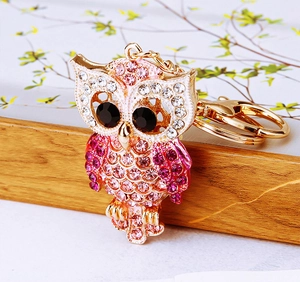 Macro shot of owl keychain with pink and white rhinestones on a gold metal frame