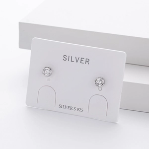 Macro detail of round zircon S925 sterling silver studs on a white jewelry display card