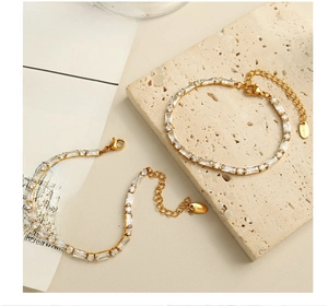 Detail of gold stainless steel bracelet with rectangular zircons on textured stone