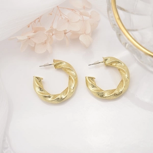 Detailed close-up of gold-plated hollow C-shaped earrings with a twisted metal texture